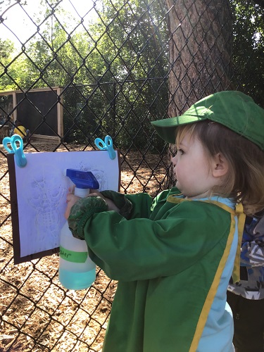 Toddler child using a spray bottle