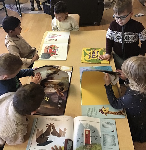 Group of preschool children reading stories about dinosaurs 