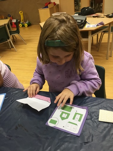 School-age girl folding origami using instructions 