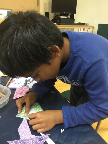 school-age boy concentrating hard on his origami 