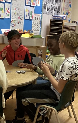3 School-age children playing the card game President