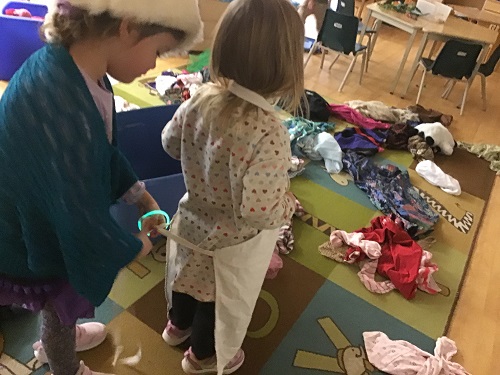 2 children tying apron for dress up 