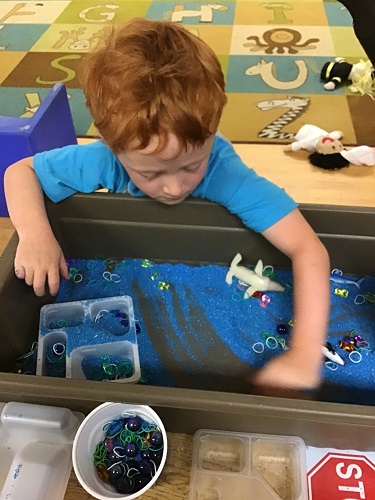 Kindergarten boy finding the items hidden in the sand