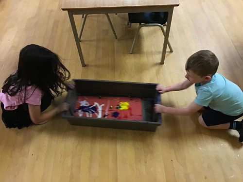 2 JKK children working together to create marble painting 