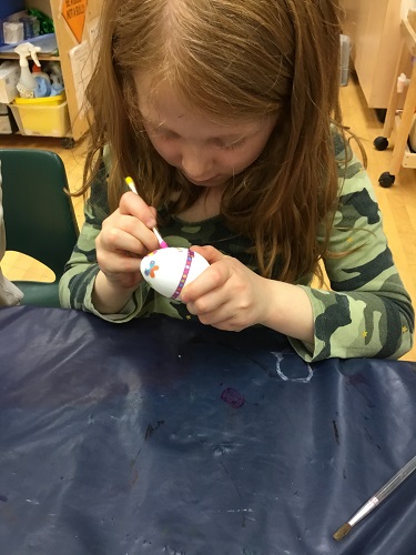 school-age girl decorating egg