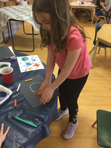 School-age girl creating a galaxy with paint 