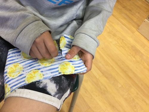 school age boy stitching fabric 