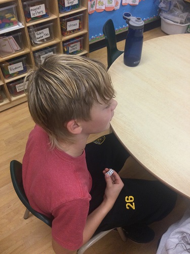 school-age boy hiding his dice number under table 