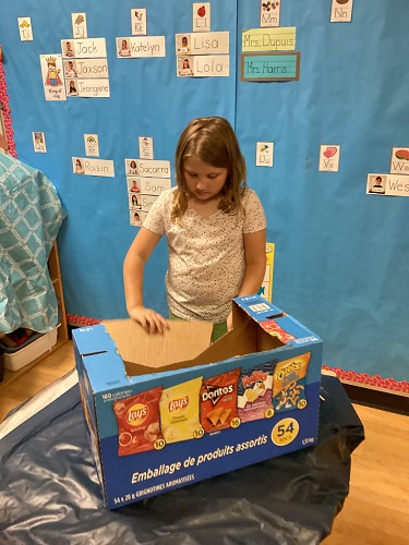 school-age girl designing and building with a box