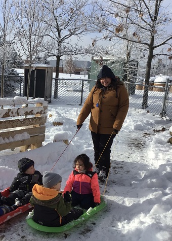 Educator pulling toddlers on sled