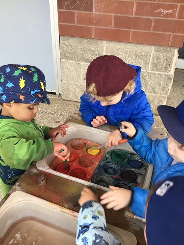 3 toddlers painting outside 