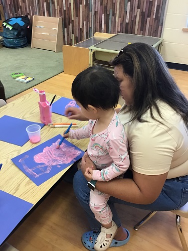 Toddler Educator and child painting together 