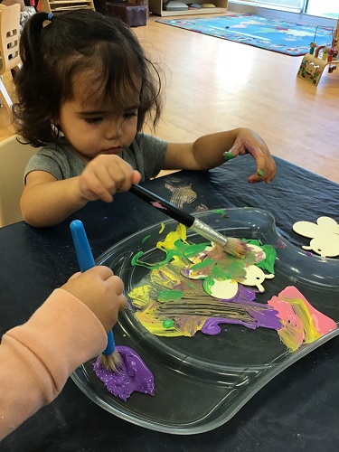 Toddler painting at table with peers