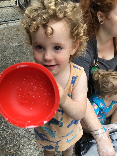 A toddler is holding up a small plunger.