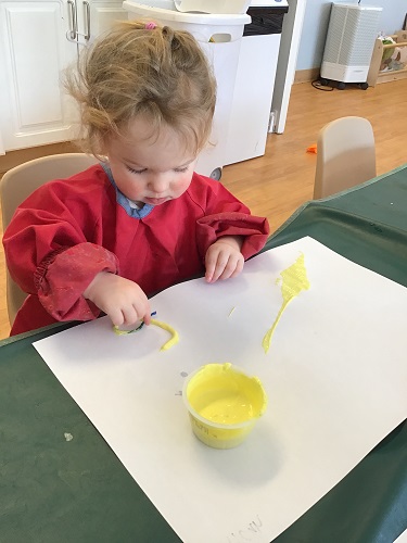 Child using the yellow paint, painting with string