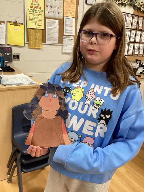 A school age child proudly showing their art work