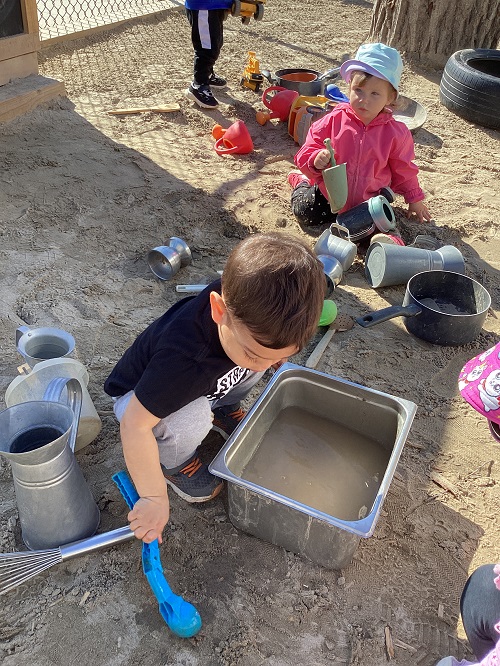 Children sitting in the sandbox exploring the sand