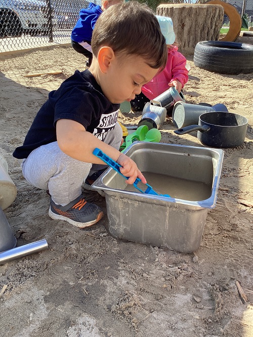 A child using a scoop with sand and water