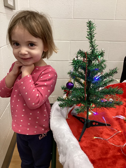 A child posing with their tree.