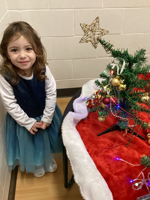 A child posing with their decorated tree.