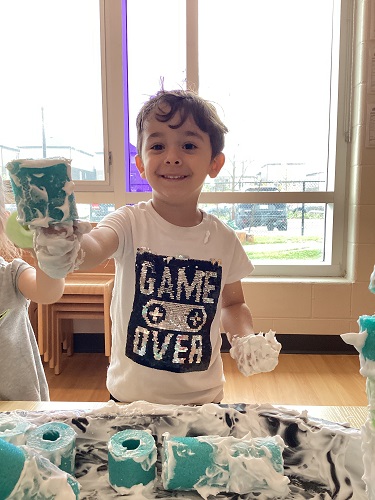 A child building a tower with the shaving cream covered pool noodles.