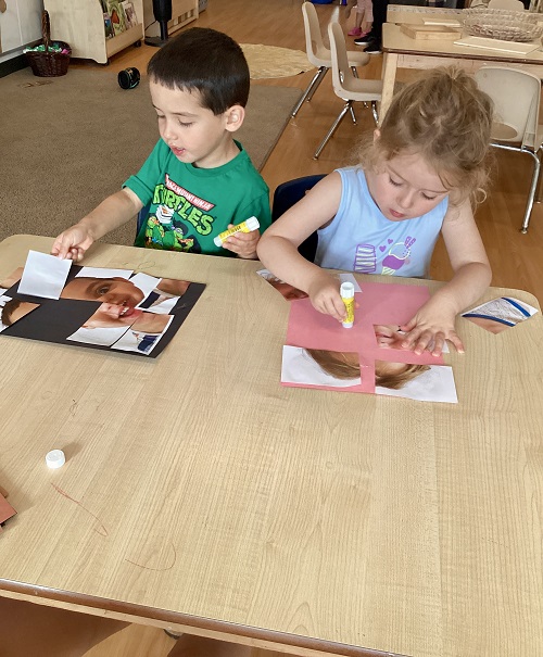 Children gluing a picture of themselves on a paper.