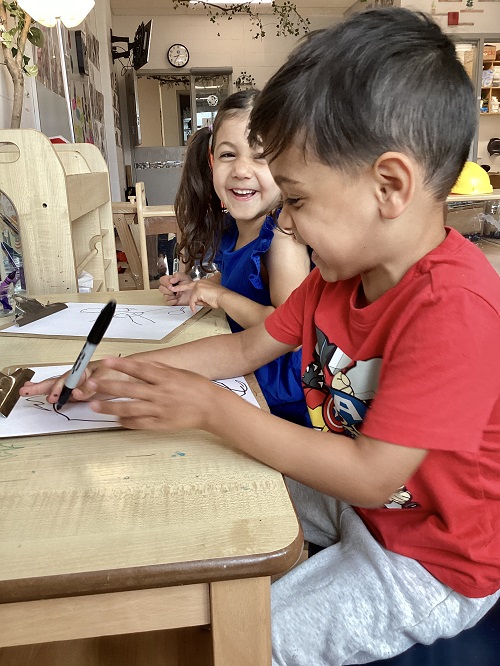 Children sitting at a table together while drawing pictures