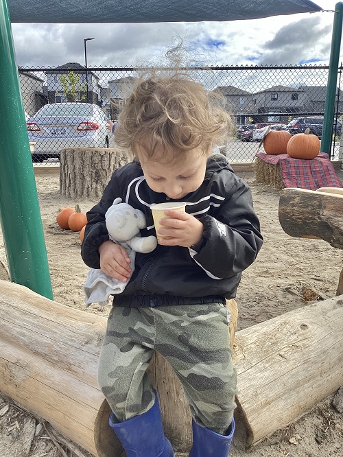 A child smelling their cup of apple cider.