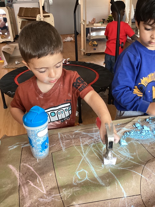 Children using a hammer on chalk.