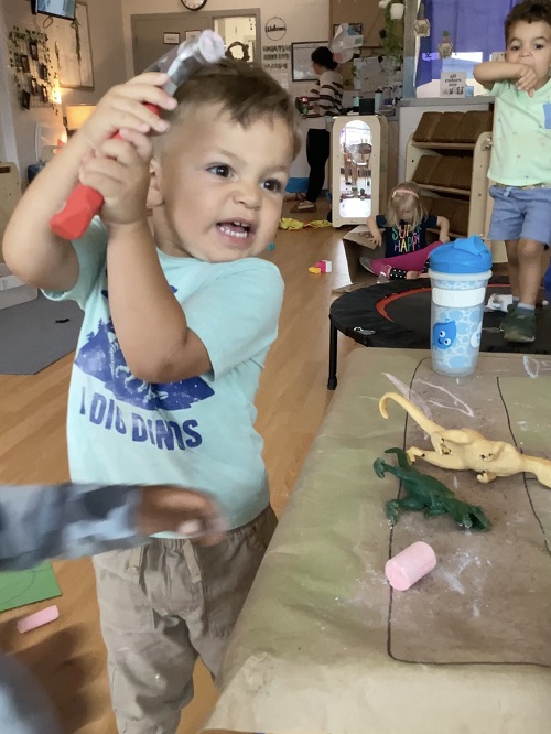 Children using a hammer on chalk.