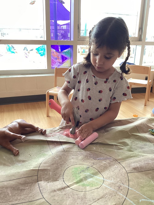 Children using a hammer on chalk.