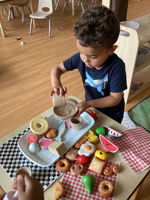 A child engaged in dramatic play while incorporating water play.