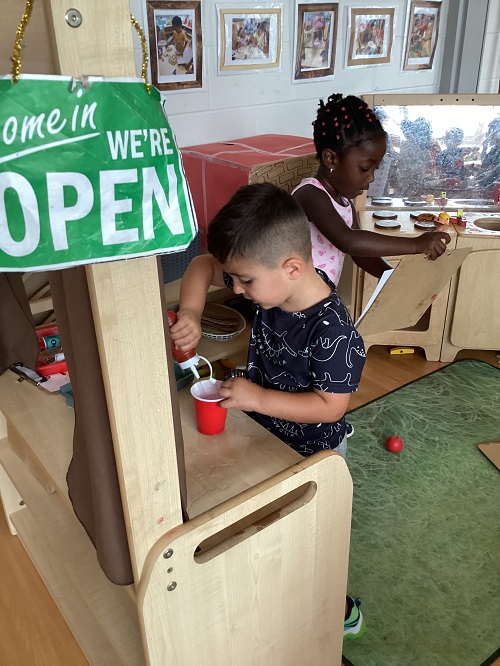 Two children exploring with water while in the dramatic play center.