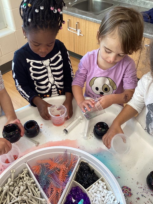 Children exploring with cups of vinegar, baking soda and loose parts.