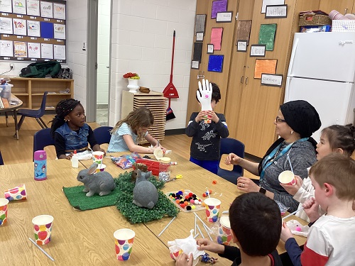 A child holding up their bunny creation.