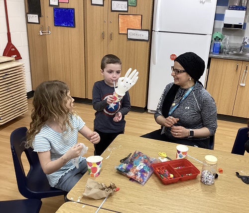 A child showing their bunny creation to their Educator and peer.