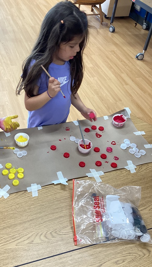 A child painting some bottle caps