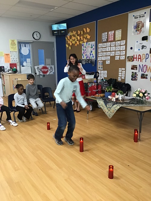 A child engaging in tradition as they jump over flameless candles.