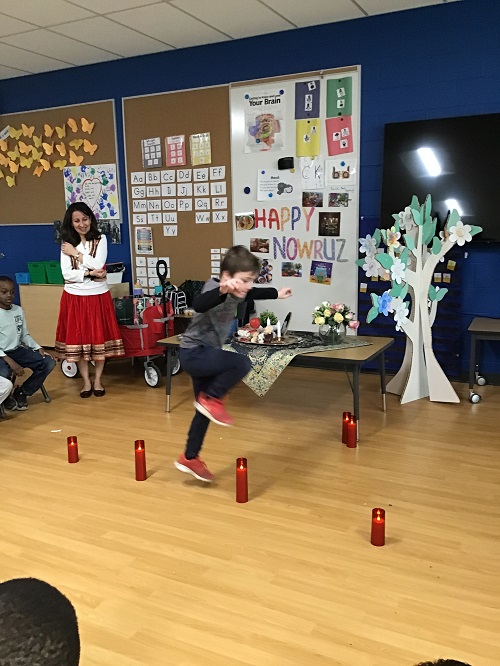 A child engaging in tradition as they jumped over a flameless candle.