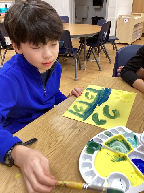 A child sitting at a table painting.