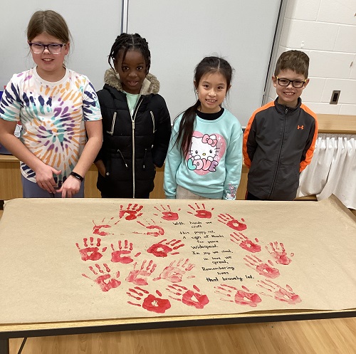 A small group of children standing in front of their artistic creation.