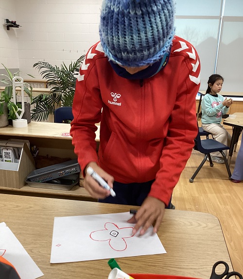 A child colouring a poppy they had created.