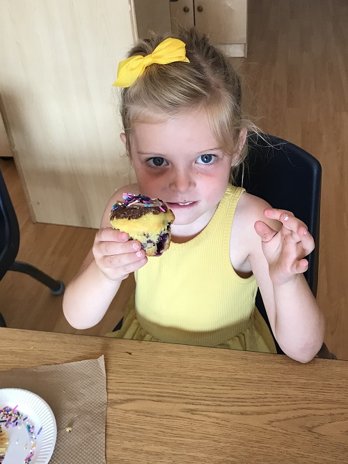 A child holding up a muffin.