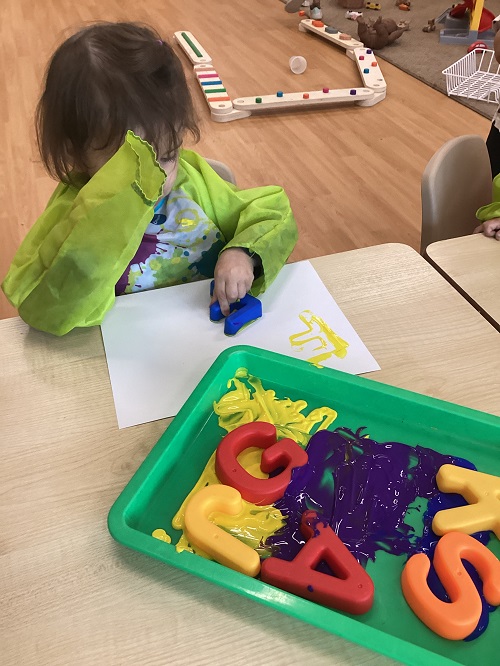 A child painting with letters.