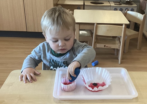 A child using their water-dropper to colour their coffee-filter poppy.