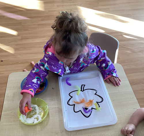 A child dipping a paint brush into glue