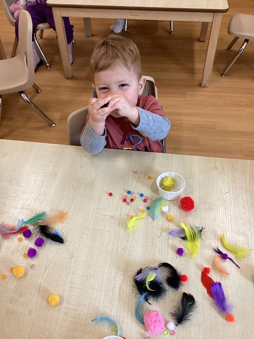 A child excitedly holding some art materials.