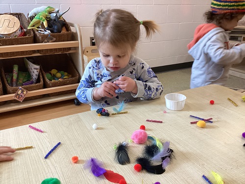 A child examining art materials in their hand.