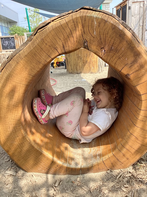 A child sitting in the tree tunnel.