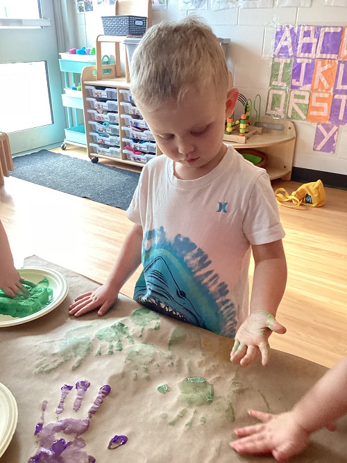 A child adding their handprint to paper